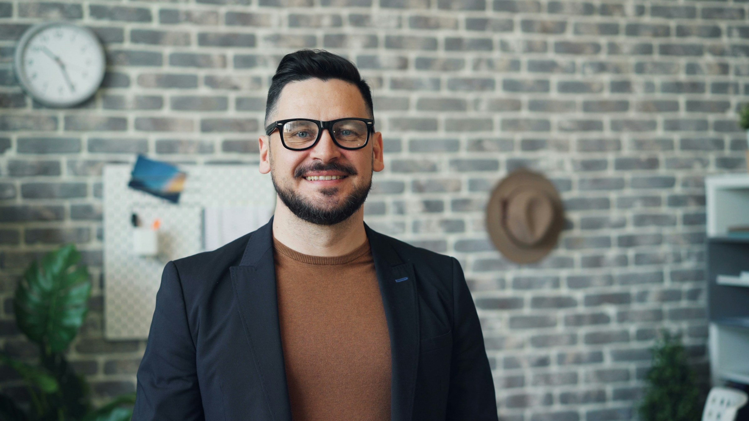 A smiling man standing in front of a brick wall | Source: Unsplash