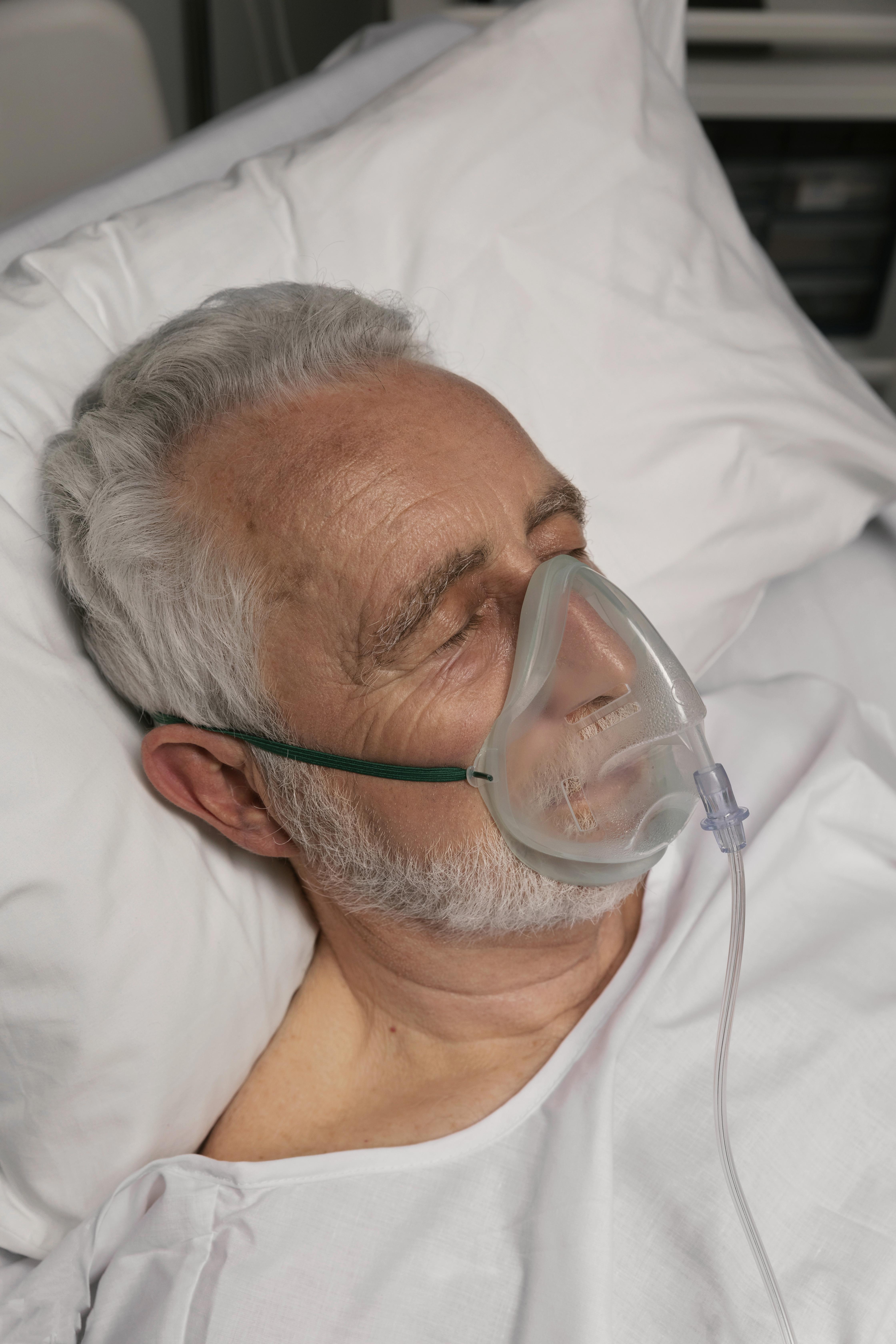 A senior man lying in a hospital bed | Source: Freepik