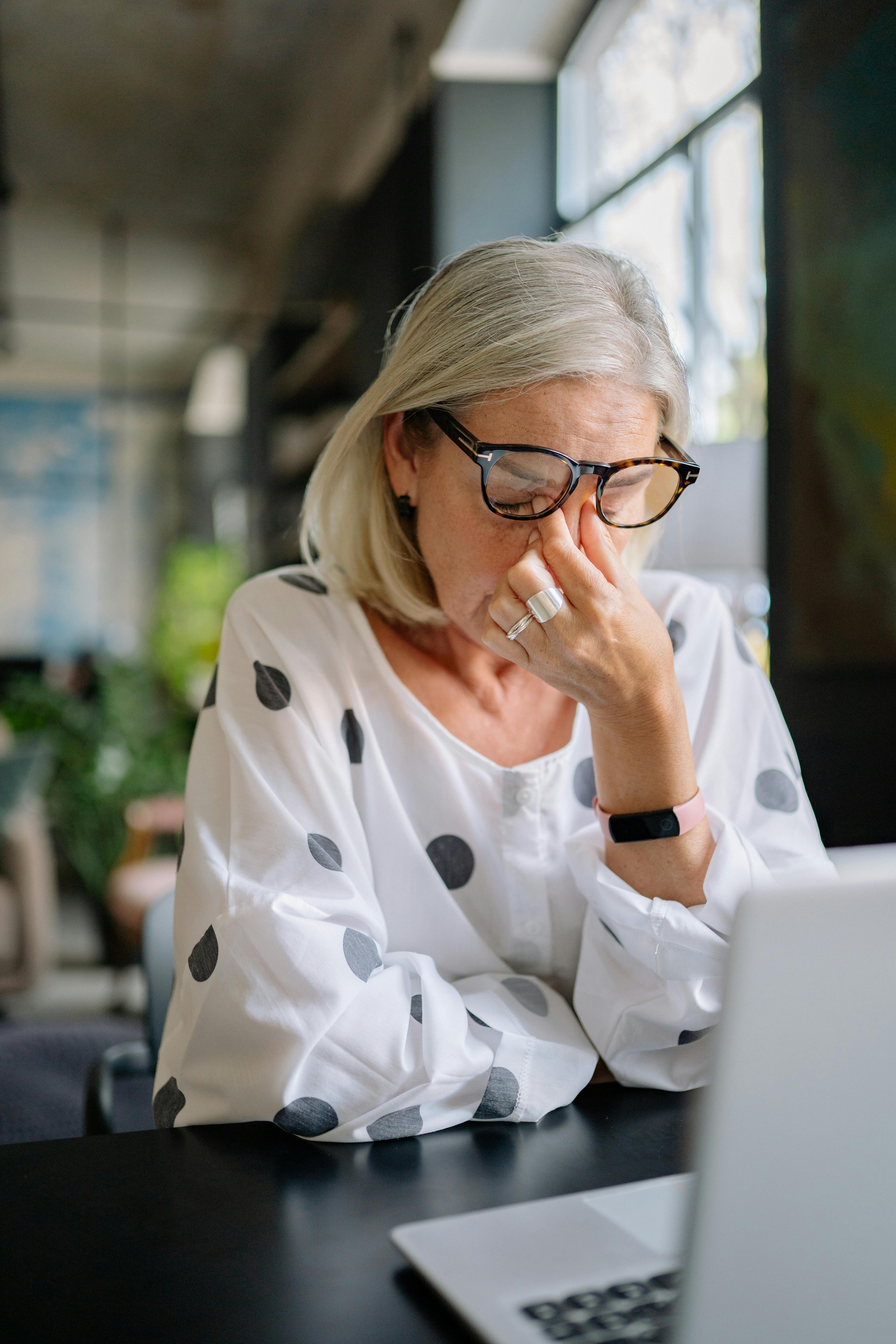 An older woman holding the bridge of her nose | Source: Pexels