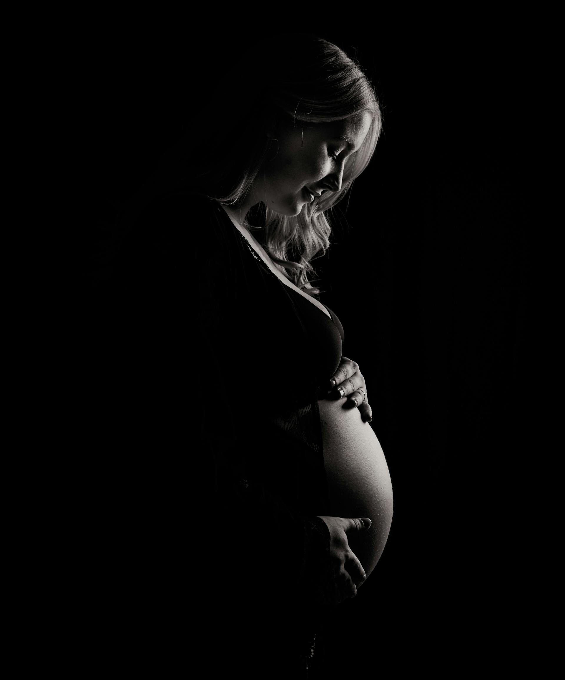 A grayscale photo of pregnant woman holding her baby bump | Source: Pexels