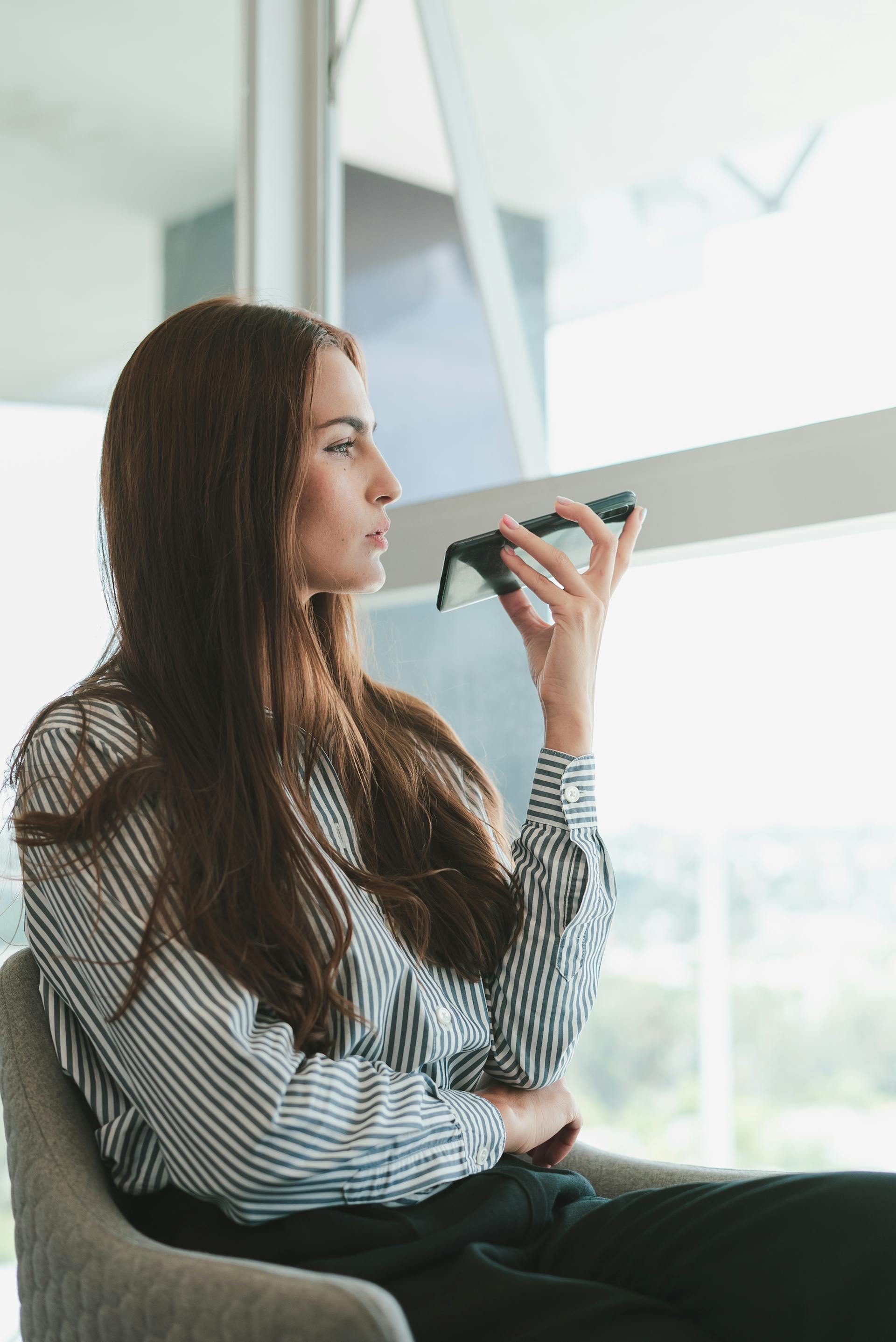 A woman sitting on a chair and talking on the phone | Source: Pexels