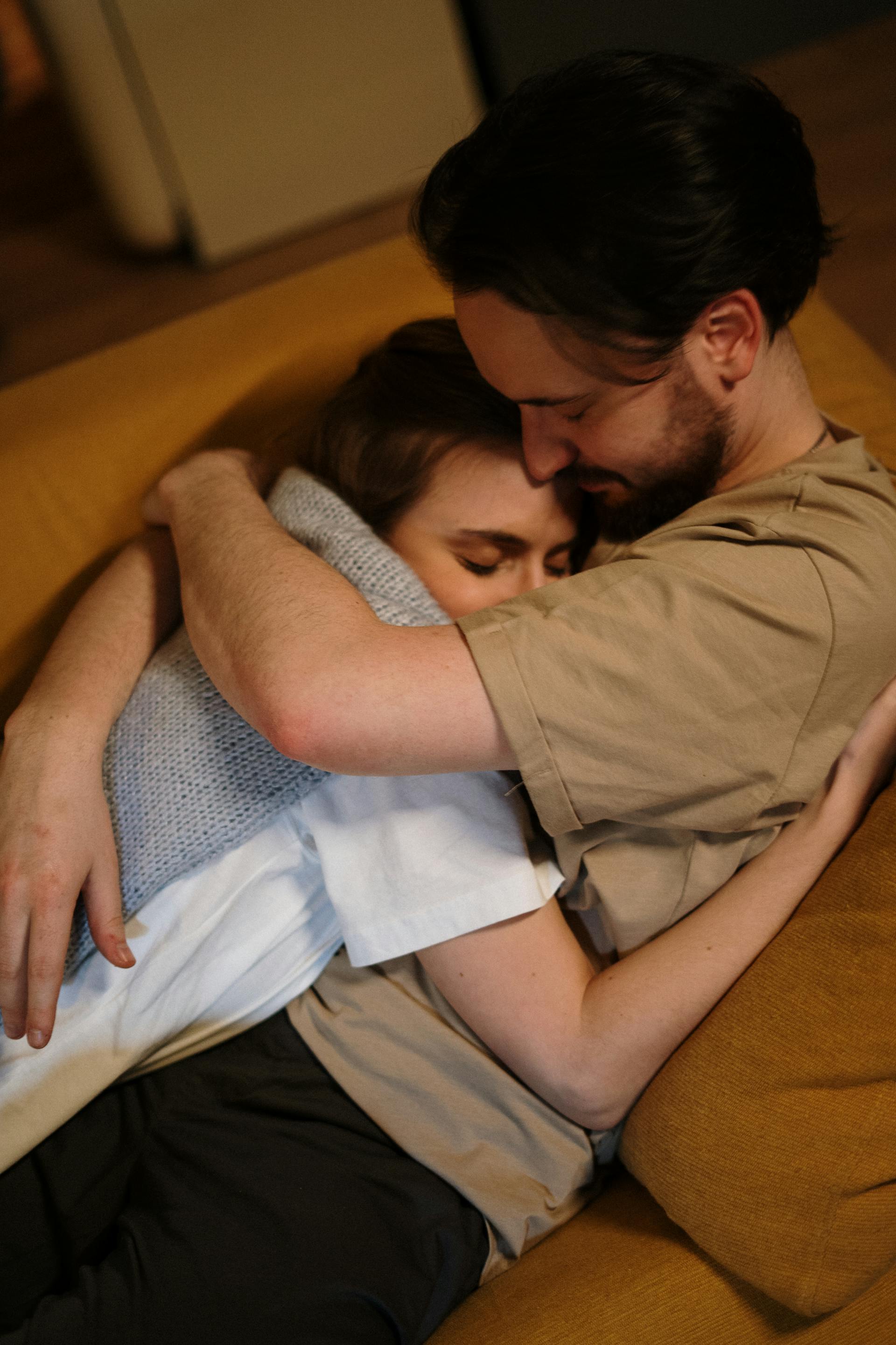 A man hugs his wife while lying on a sofa | Source: Pexels