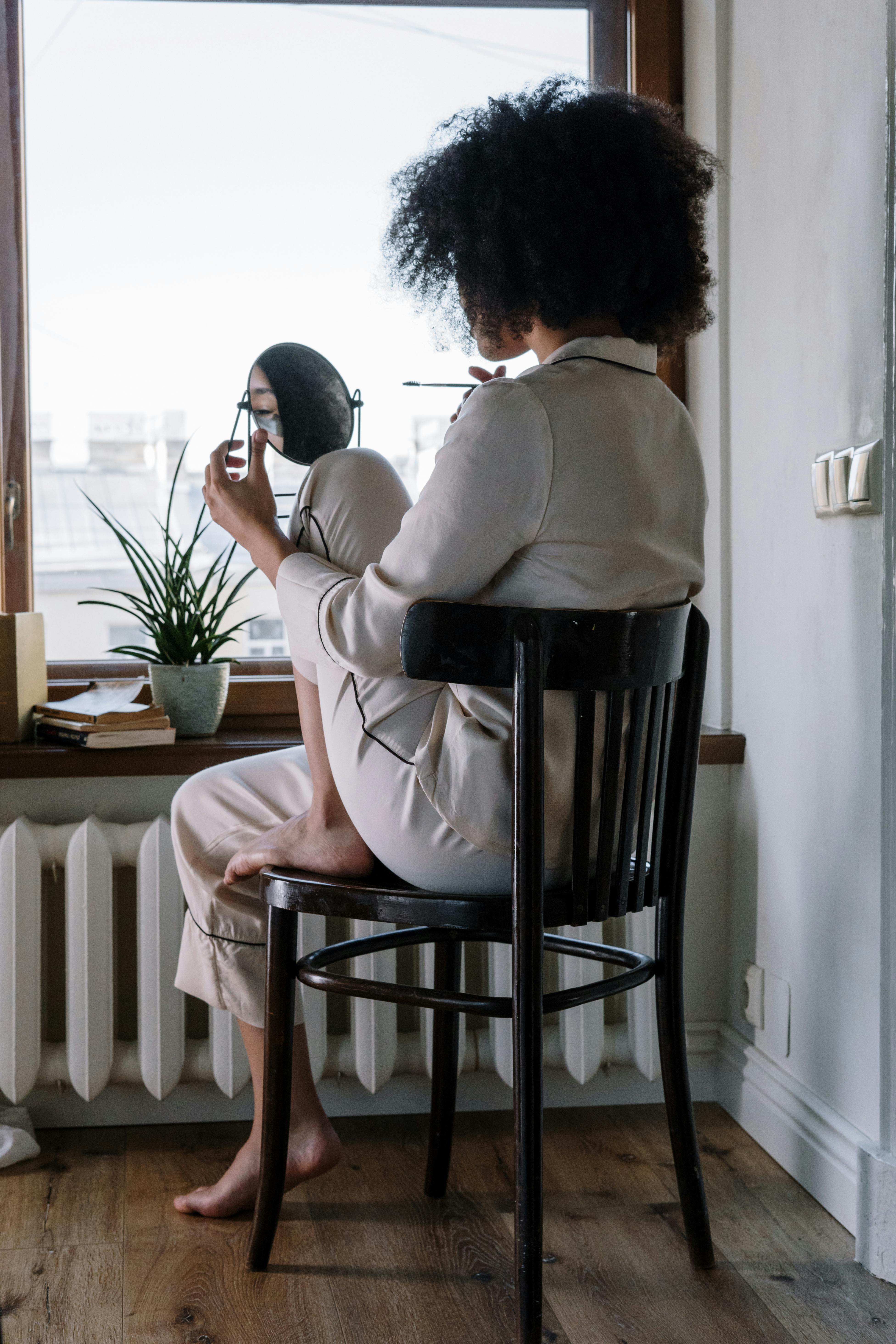 A woman wearing pajamas while looking at herself in a mirror | Source: Pexels