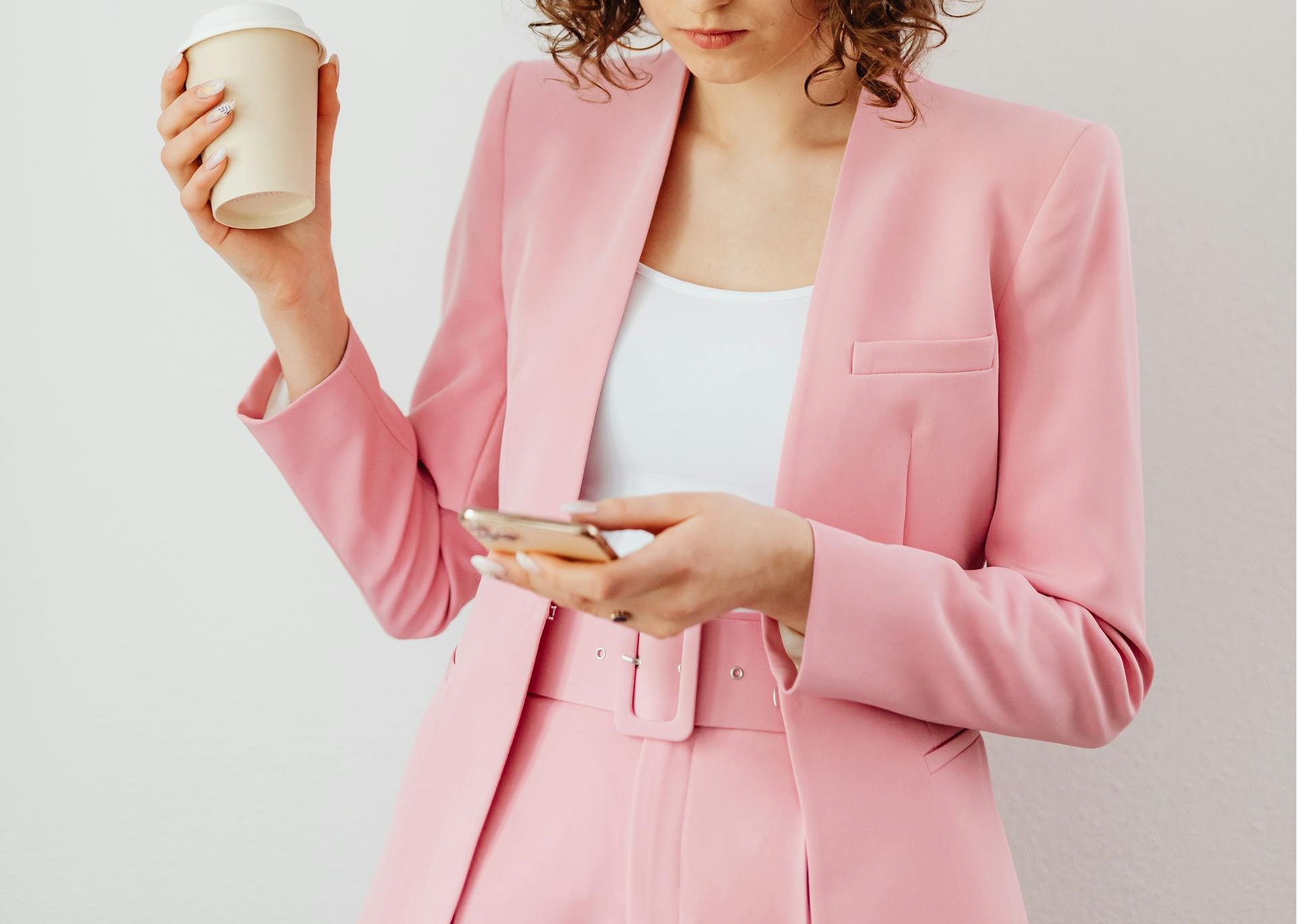 A woman in pink suit holding a smartphone | Source: Pexels